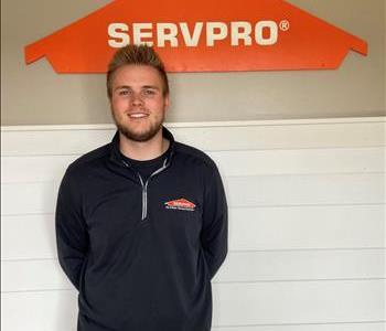 A young man standing in front of the SERVPRO of St. Cloud trailer.