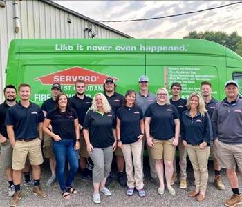 Men and women employees of SERVPRO of St. Cloud standing in front of the six vehicles. 