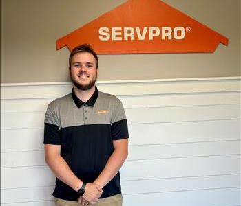 A young man standing in front of the SERVPRO of St. Cloud trailer.